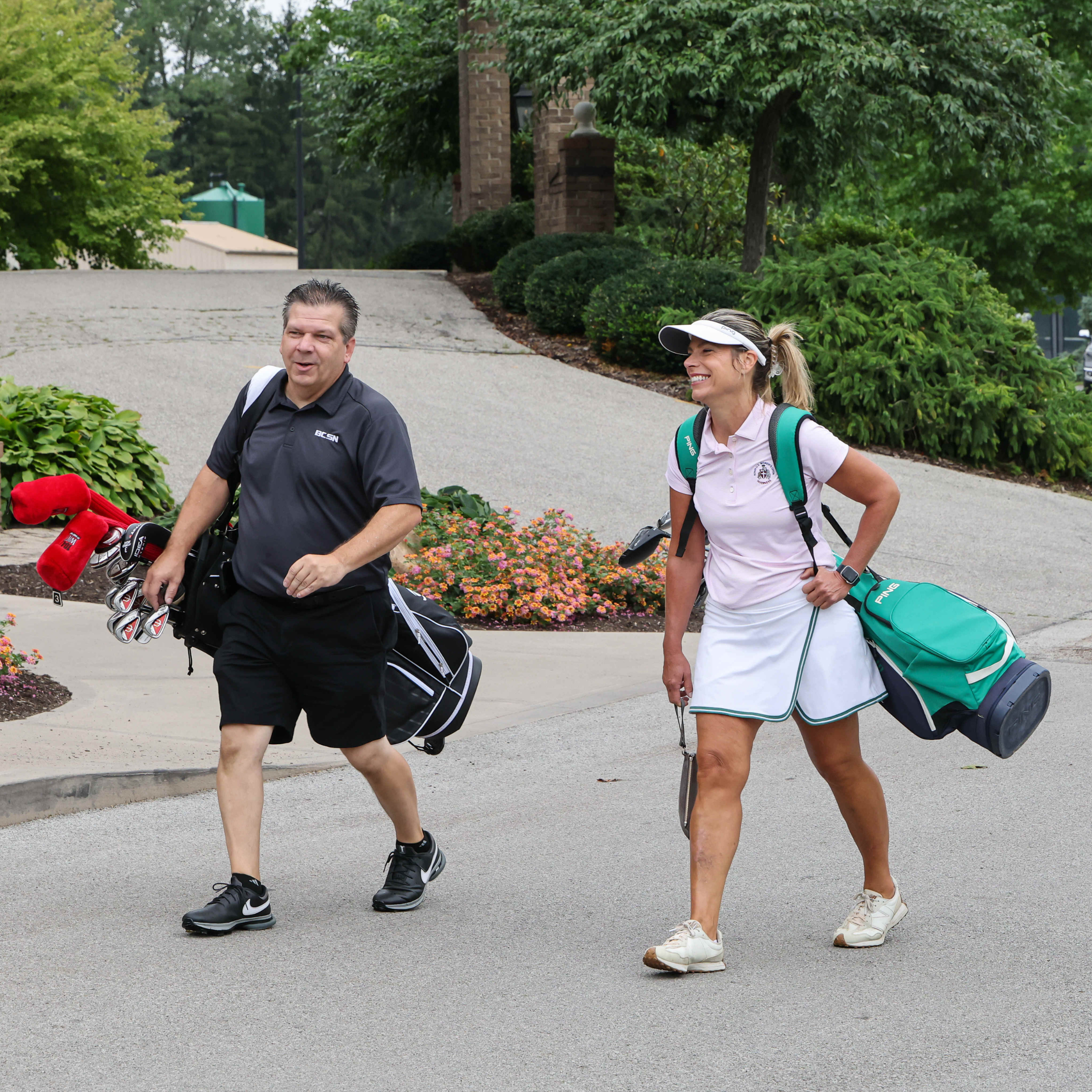 man and woman walking with golf clubs to their next hole